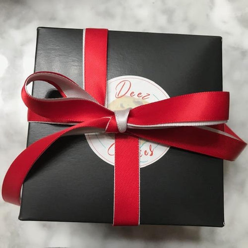 4x4 black box with Deez Cookies logo wrapped with double satin red and grey ribbon tied in a tiffany bow